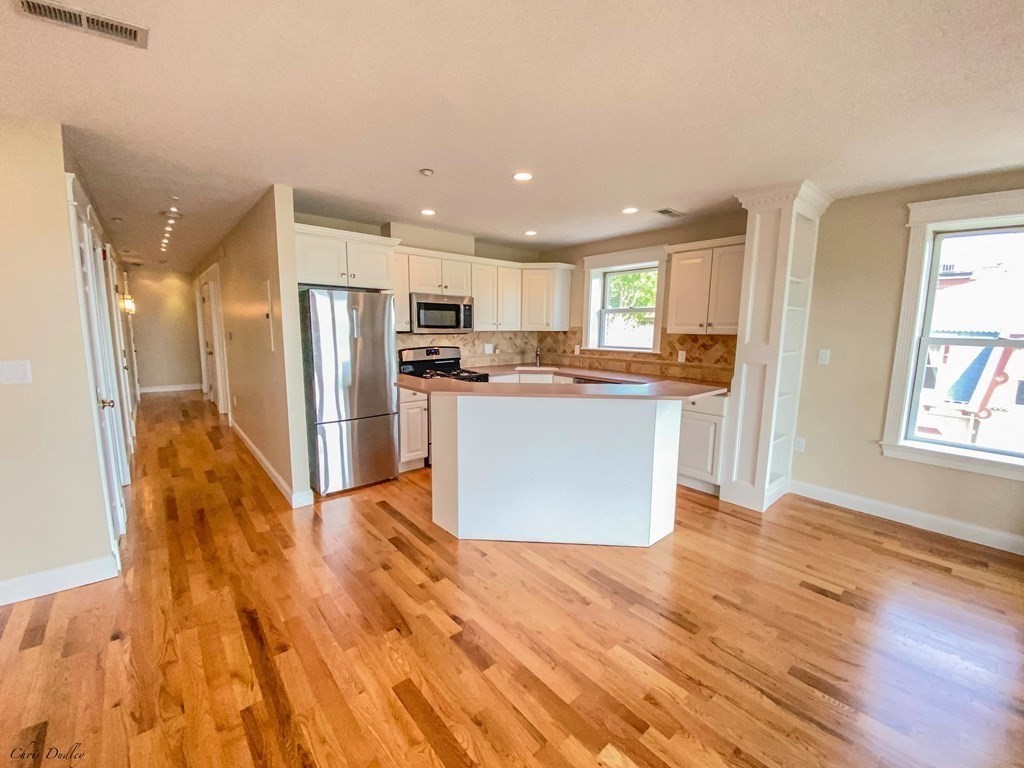 53 Thomas Park, Unit 9 Boston, MA 02127 - Photo 3 of 41 a kitchen with stainless steel appliances granite countertop a refrigerator a sink dishwasher a stove and white countertops with wooden floor