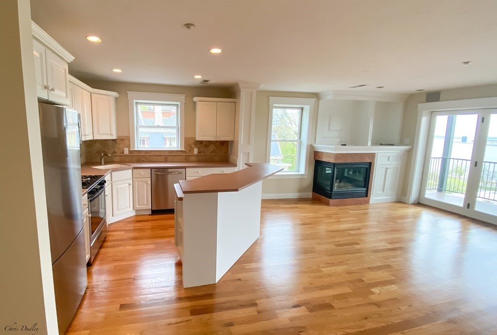 53 Thomas Park, Unit 9 Boston, MA 02127 - Photo 7 of 41 a kitchen with stainless steel appliances granite countertop a refrigerator a stove top oven a sink dishwasher and a fireplace with wooden floor
