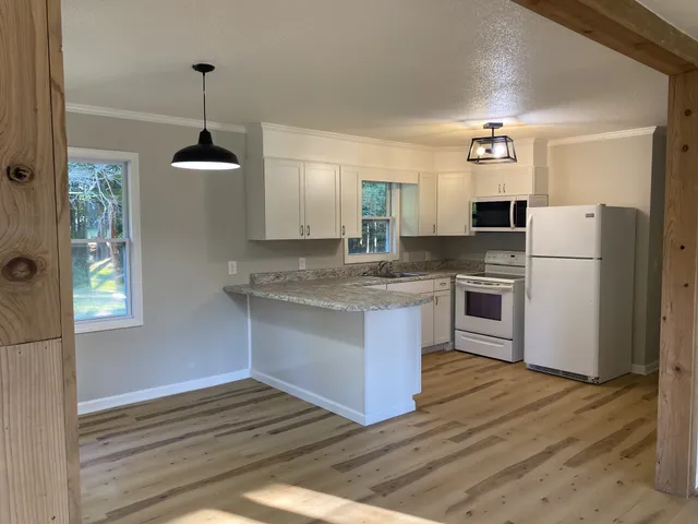 a kitchen with granite countertop a refrigerator a stove a sink cabinets and wooden floor