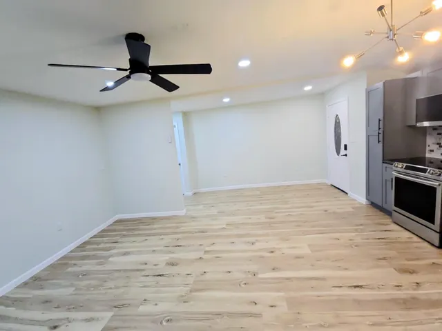 a view of empty room with wooden floor and fan