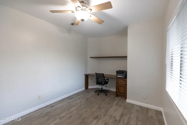 an empty room with ceiling fan and window