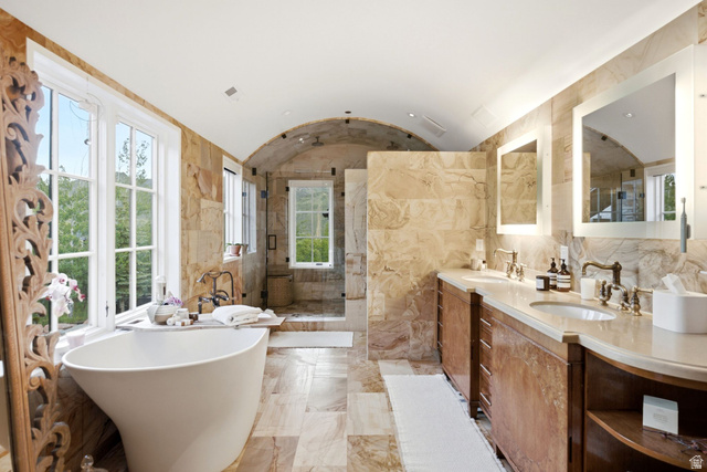 5971 Maple Ridge Trail Oakley, UT 84055 - Photo 25 of 43 Spacious bathroom featuring a freestanding soaking tub, dual vanity with undermount sinks, stone tile flooring, arched ceiling, and large windows