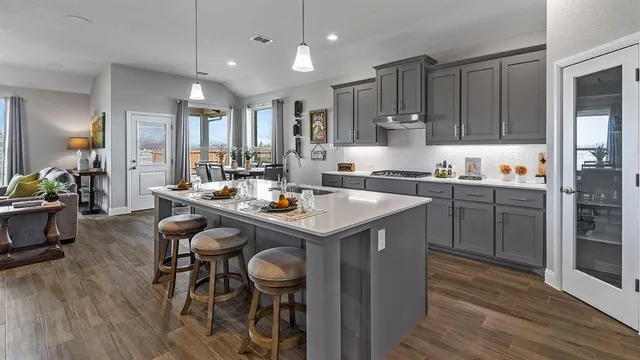 a kitchen with stainless steel appliances granite countertop a sink a stove a refrigerator cabinets and dining table