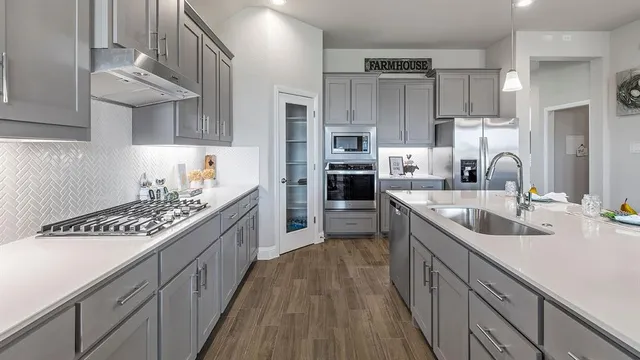 a kitchen with a sink a stove cabinets and wooden floor