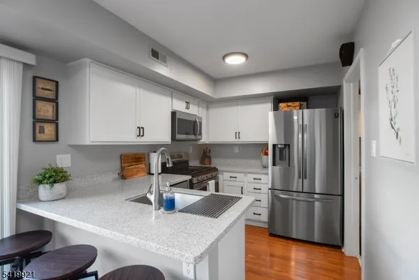 a kitchen with stainless steel appliances granite countertop a refrigerator a stove a sink a microwave and a refrigerator