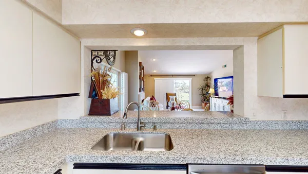 a view of a kitchen counter top space with sink and mirror