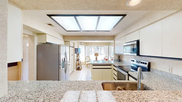 a kitchen with stainless steel appliances kitchen island granite countertop a refrigerator and a sink
