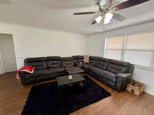 a living room with couches and a ceiling fan with wooden floor