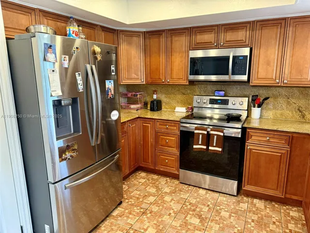 a kitchen with stainless steel appliances granite countertop a refrigerator stove a sink and a microwave