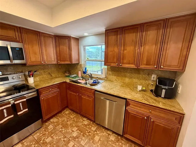 a kitchen with granite countertop wooden cabinets stainless steel appliances and a sink