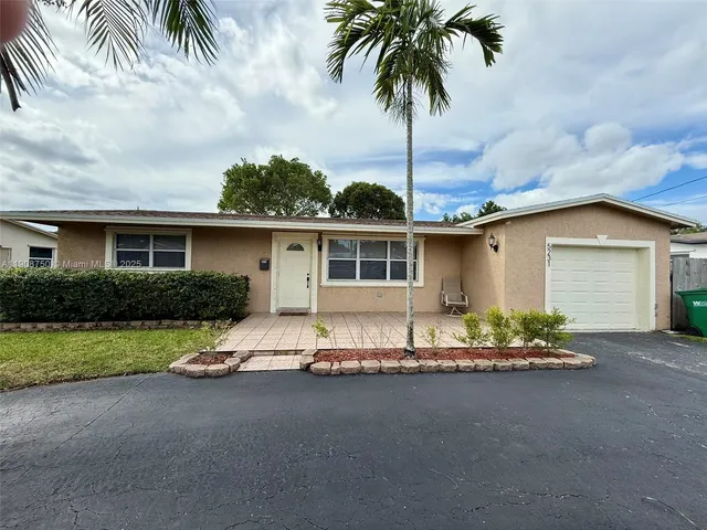 front view of house with a yard and palm trees