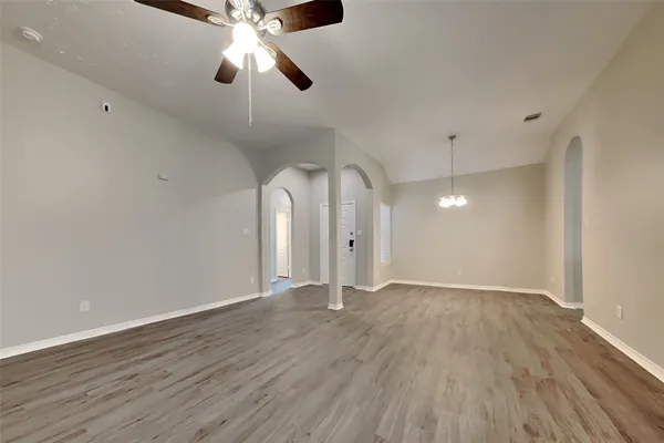 an empty room with wooden floor chandelier fan and closet area