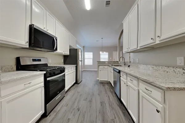 a kitchen with stainless steel appliances granite countertop a sink a stove top oven and cabinetry