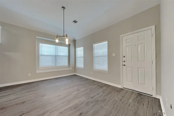 an empty room with wooden floor cabinet and windows