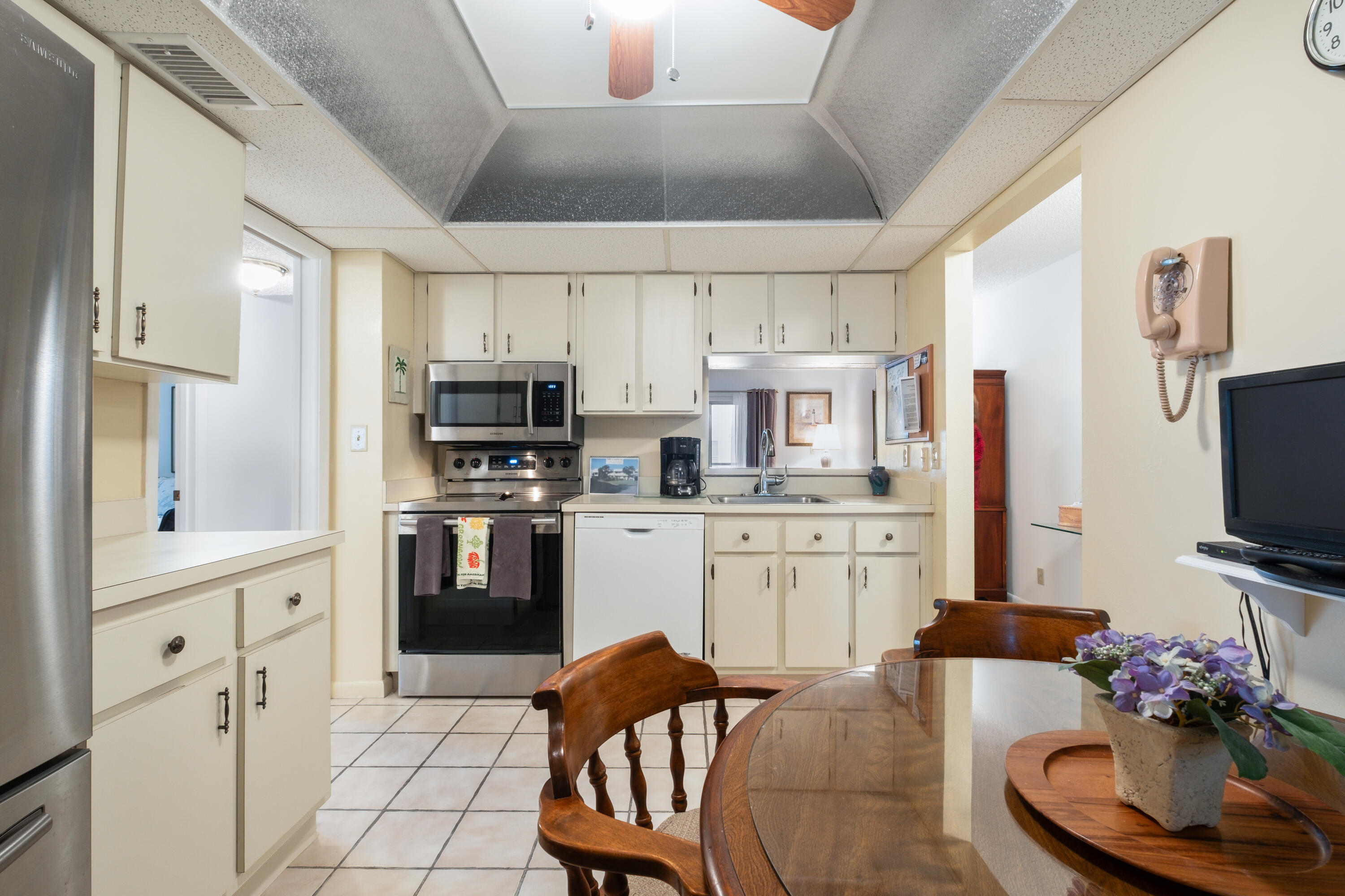 a kitchen with stainless steel appliances kitchen island granite countertop a sink dishwasher a stove a microwave oven a refrigerator with white cabinets and wooden floor