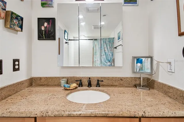 a bathroom with a granite countertop sink and a mirror