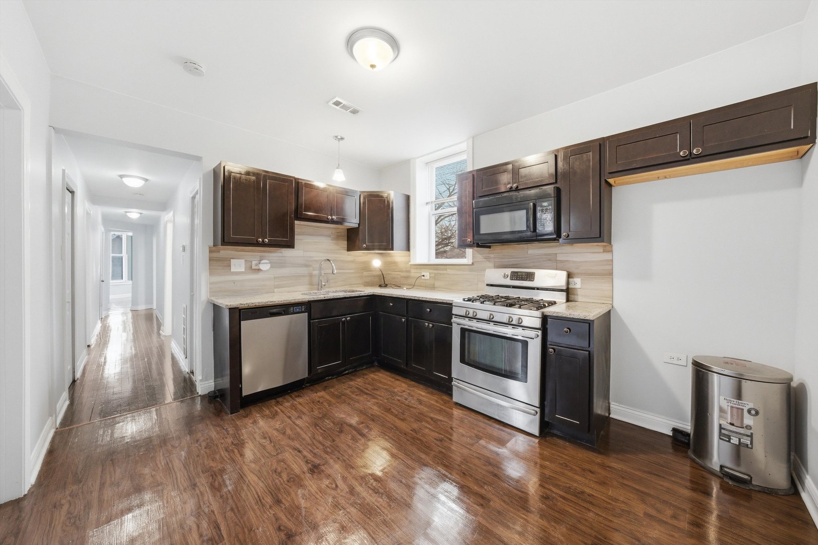 7242 South May Street, Unit 2 Chicago, IL 60621 - Photo 8 of 12 a kitchen with stainless steel appliances kitchen island granite countertop a stove top oven a sink and a microwave