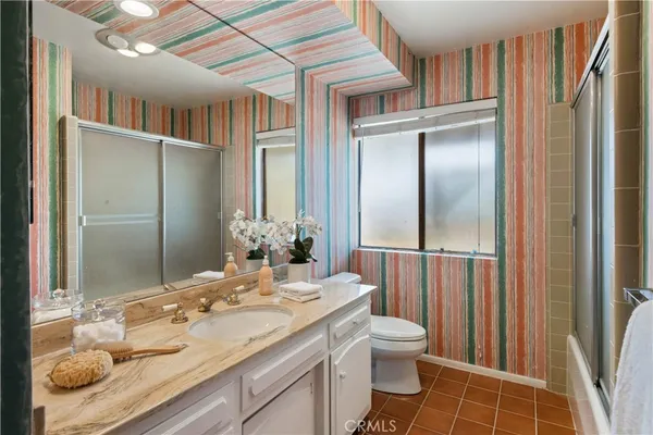a bathroom with a granite countertop sink a toilet and shower