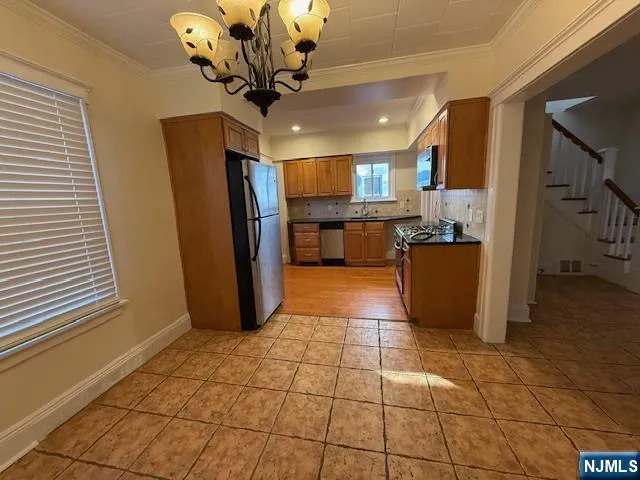 a kitchen with stainless steel appliances granite countertop a refrigerator a stove a sink a washer dryer and a dining table