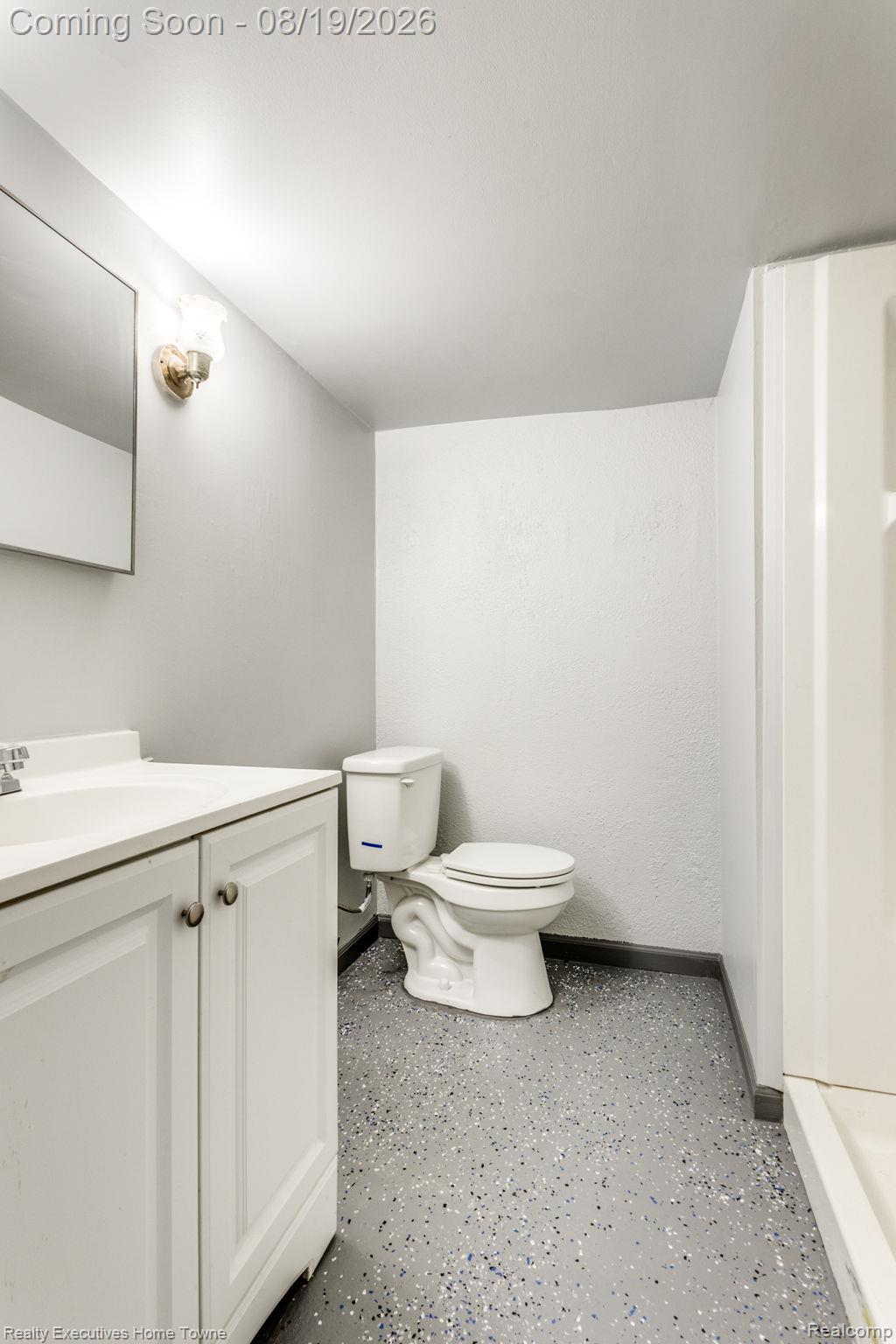 2448 Oakcrest Road Sterling Heights, MI 48310 - Photo 23 of 31 White vanity with a single basin sink, wall-mounted mirror, and speckled flooring