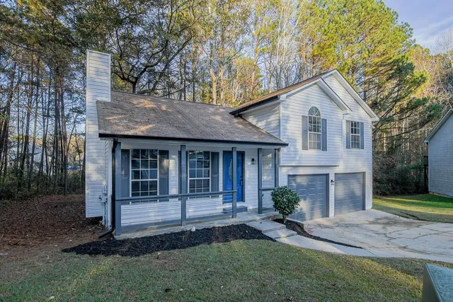 a view of a house with a yard and large tree