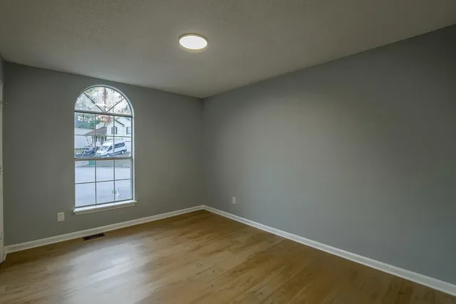 an empty room with wooden floor and windows