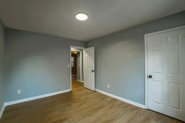 a view of an empty room with wooden floor and closet