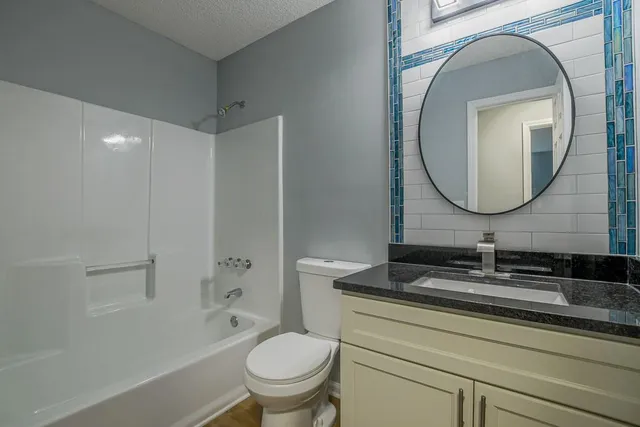 a bathroom with a granite countertop toilet sink and mirror