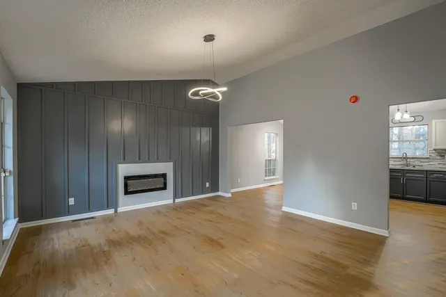 a view of empty room with kitchen and fireplace