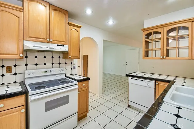 a kitchen with granite countertop a stove a sink and a refrigerator
