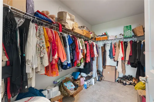 a view of walk in closet with clothes and shoes