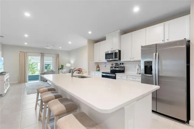 a large kitchen with kitchen island a large counter top space a sink stainless steel appliances and cabinets