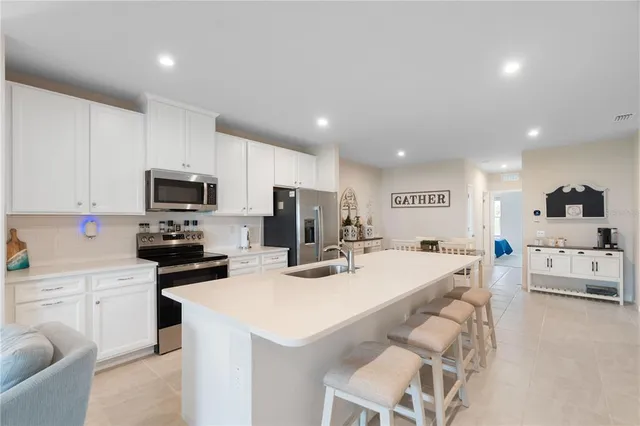 a kitchen with stainless steel appliances a stove a sink a microwave a refrigerator and white cabinets