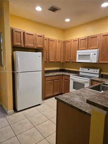 a kitchen with stainless steel appliances granite countertop a refrigerator a sink and a stove