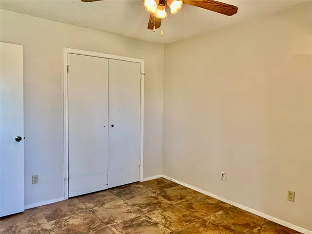 an empty room with a window and ceiling fan