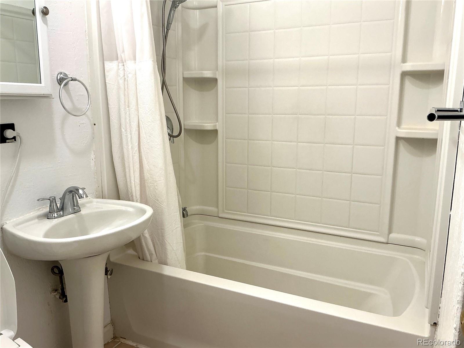 Undisclosed Address Aurora, CO 80010 - Photo 14 of 23 a white bath tub sitting next to a white sink and a mirror