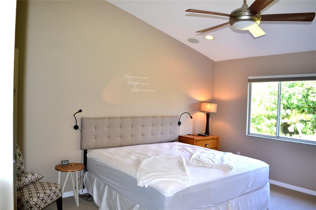 11158 Kapok Grand Circle Madeira Beach, FL 33708 - Photo 16 of 48 a bedroom with a bed and a chandelier