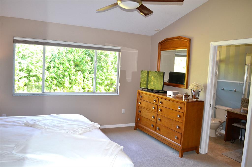 11158 Kapok Grand Circle Madeira Beach, FL 33708 - Photo 18 of 48 a bedroom with a bed and a flat tv screen on dresser