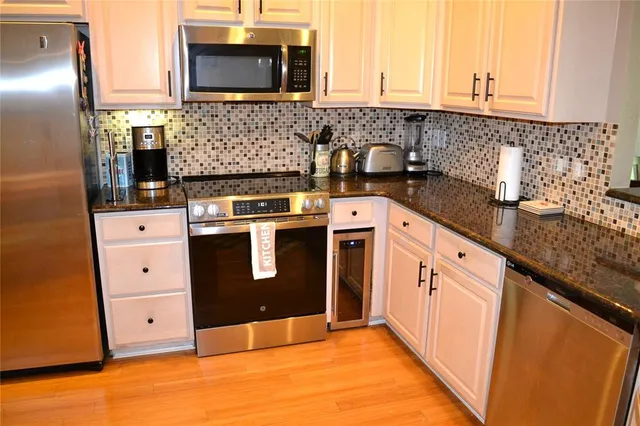 a kitchen with stainless steel appliances granite countertop a stove a sink and a microwave