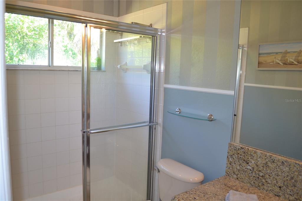 11158 Kapok Grand Circle Madeira Beach, FL 33708 - Photo 21 of 48 a bathroom with a granite countertop window a toilet and a shower