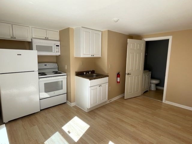 136 Brookside Road Orange, MA 01364 - Photo 4 of 10 a kitchen with a refrigerator a stove top oven a sink and cabinets