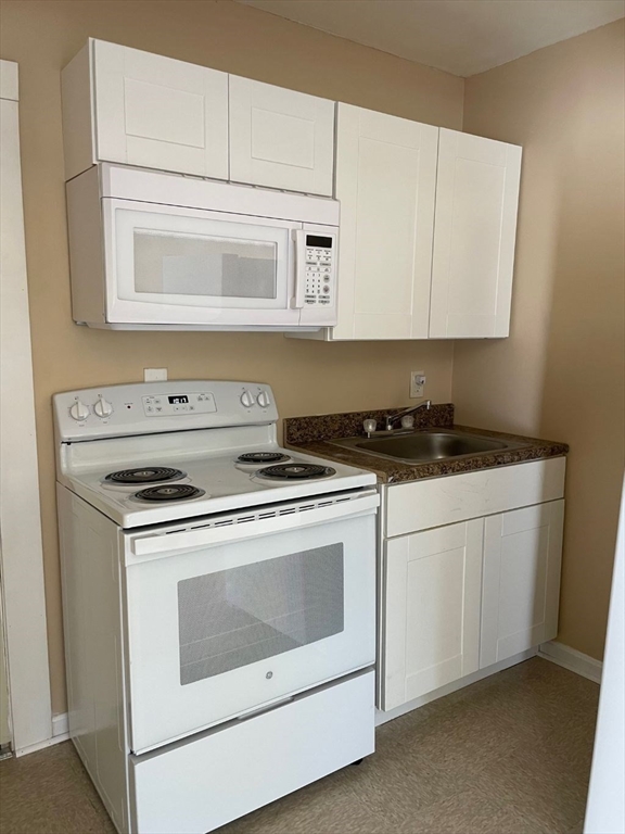 136 Brookside Road Orange, MA 01364 - Photo 5 of 10 a kitchen with white cabinets and white appliances