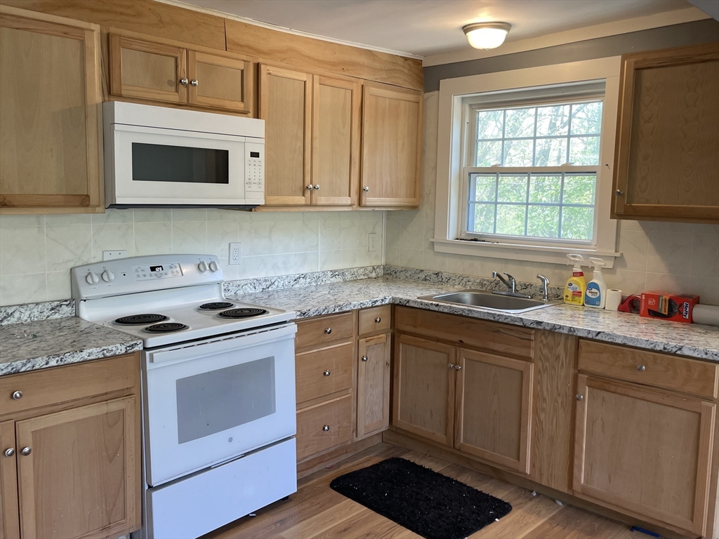 136 Brookside Road Orange, MA 01364 - Photo 9 of 10 a kitchen with granite countertop white cabinets and white appliances
