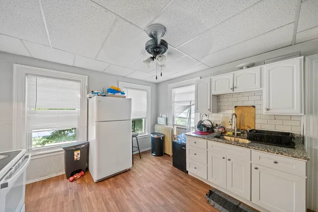 a kitchen with a refrigerator a white cabinets and wooden floor