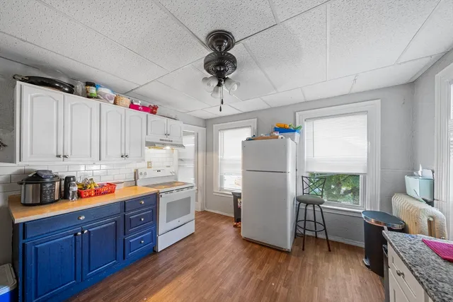 a kitchen with stainless steel appliances granite countertop a refrigerator a sink dishwasher a stove and white countertops with wooden floor