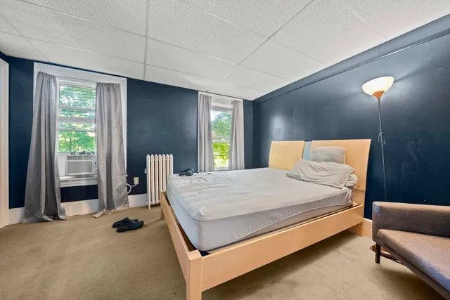 a bedroom with a bed and large windows