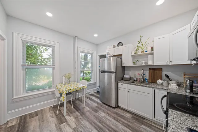 a living room with stainless steel appliances kitchen island granite countertop furniture and a wooden floor