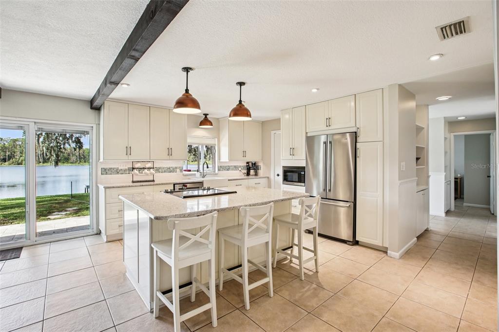 19254 Blount Road Lutz, FL 33558 - Photo 4 of 35 a kitchen with stainless steel appliances kitchen island granite countertop a refrigerator a stove a sink dishwasher and a dining table with wooden floor