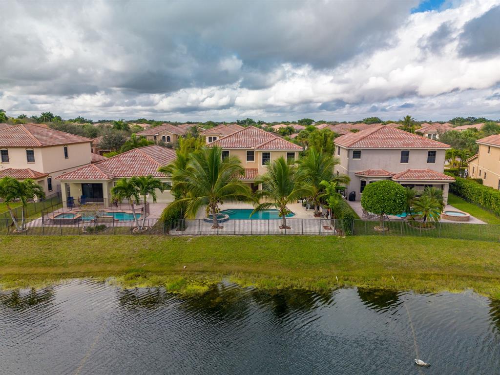 7302 Northwest 111th Way Parkland, FL 33076 - Photo 36 of 36 a view of a house with a big yard and a large pool with table and chairs under an umbrella