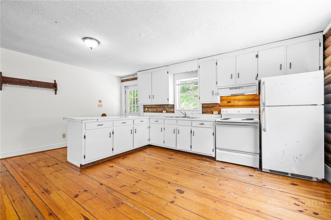 233 Alpine Acres Road Vilas, NC 28692 - Photo 9 of 32 a kitchen with white cabinets and wooden floors